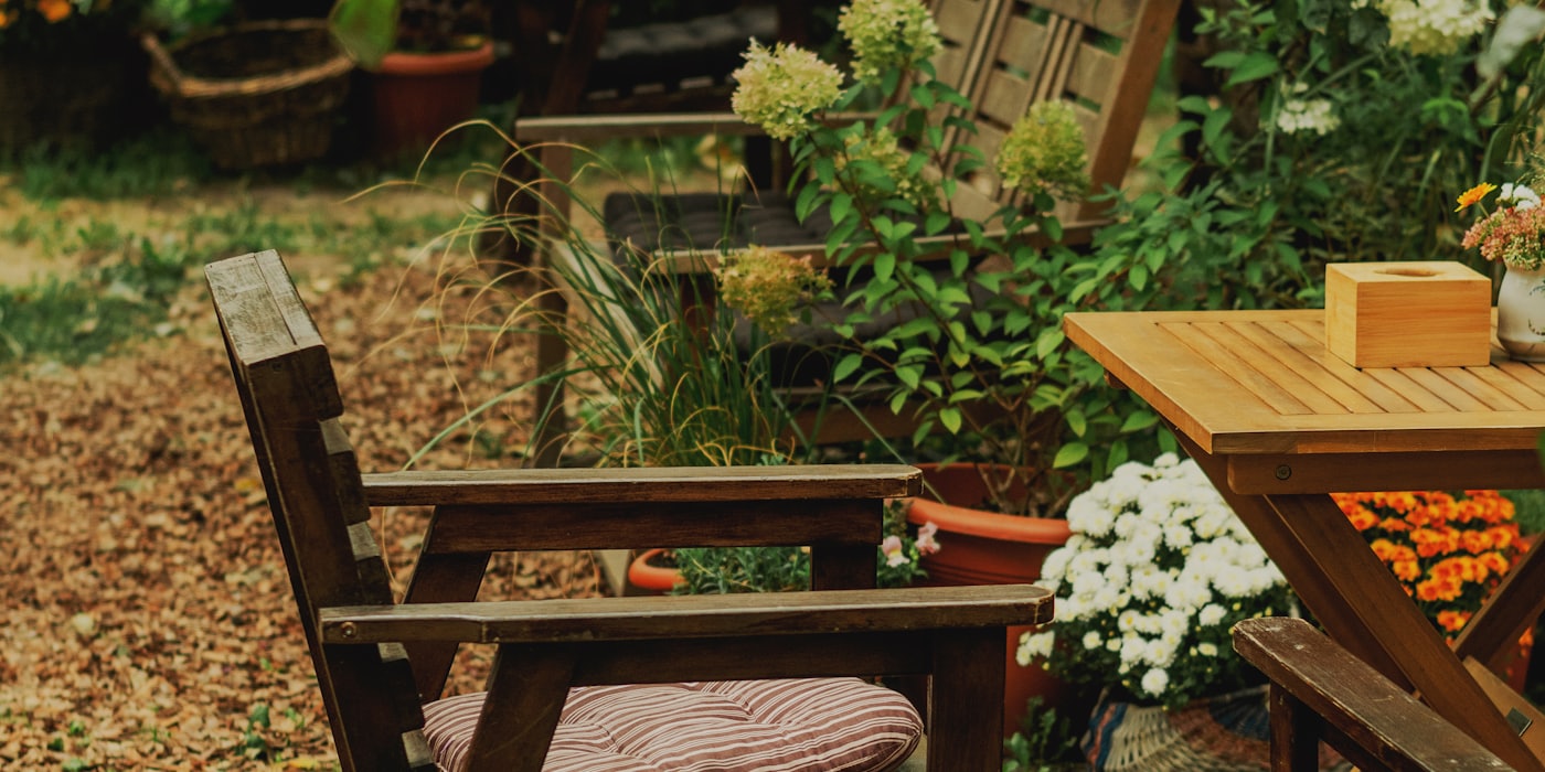 Gemütlicher Garten mit Holzmöbeln und Blumen