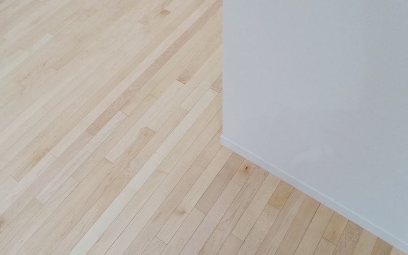 Holzboden mit weißer Wand und Sockelleiste